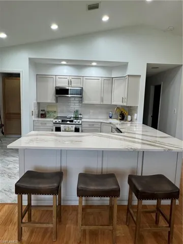 Kitchen with a kitchen breakfast bar, white range oven, kitchen peninsula, and vaulted ceiling