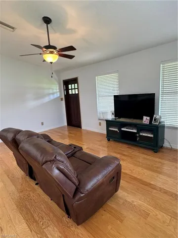Living room with light hardwood / wood-style floors and ceiling fan