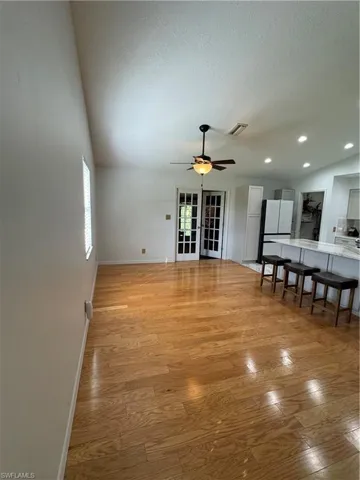 Unfurnished living room featuring ceiling fan, a textured ceiling, light wood-type flooring, and french doors