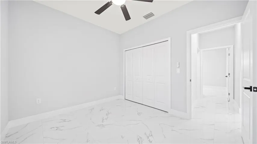 Unfurnished bedroom featuring light marble finish flooring, a closet, and ceiling fan