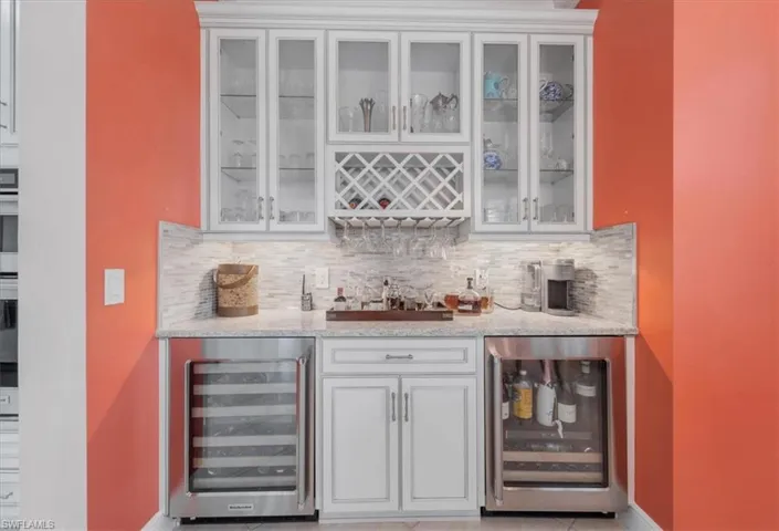Indoor bar featuring wine cooler and tasteful backsplash