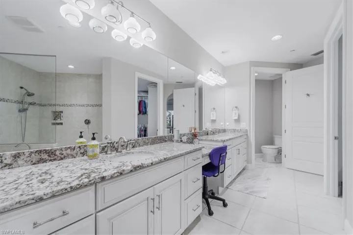 Full bath with double vanity, walk in shower, a walk in closet, and recessed lighting