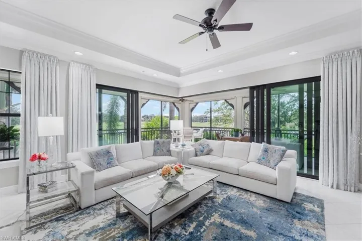 Living room with ornamental molding, recessed lighting, ceiling fan, tile patterned floors, and a tray ceiling