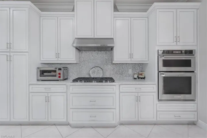 Kitchen with stainless steel appliances, light countertops, light tile patterned floors, and wall chimney exhaust hood