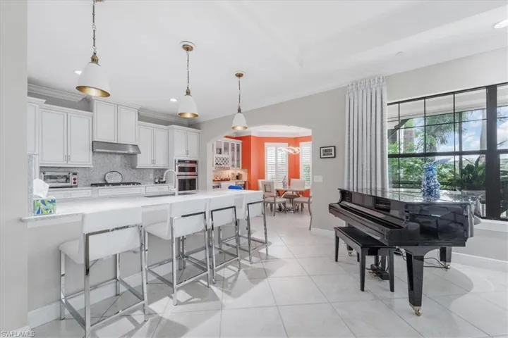 Kitchen with arched walkways, plenty of natural light, a breakfast bar area, backsplash, and crown molding