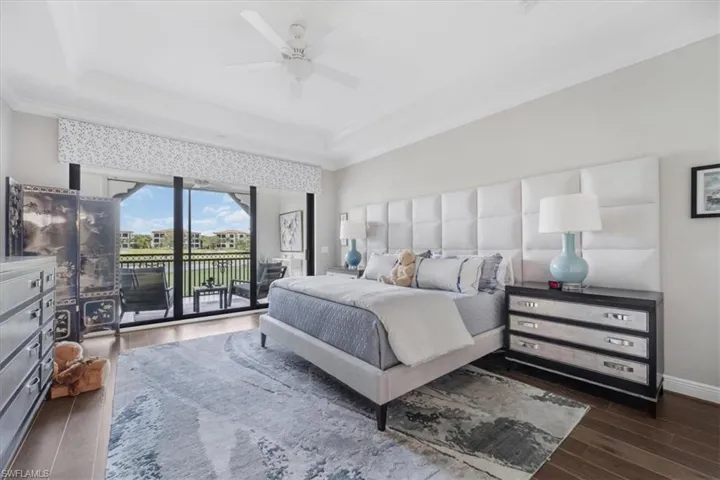 Bedroom featuring access to outside, wood finished floors, a tray ceiling, crown molding, and a ceiling fan