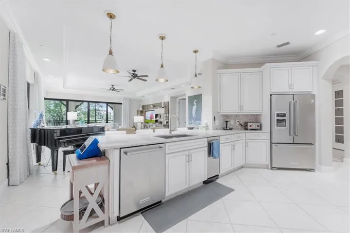 Kitchen featuring a peninsula, stainless steel appliances, a ceiling fan, arched walkways, and white cabinets