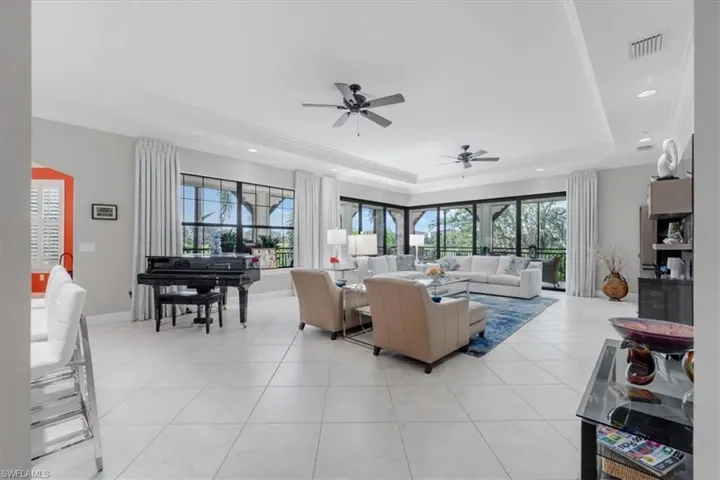 Living room featuring a raised ceiling, a ceiling fan, light tile patterned floors, and recessed lighting