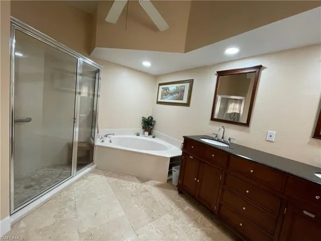 Full bathroom with vanity, a garden tub, a stall shower, and a ceiling fan
