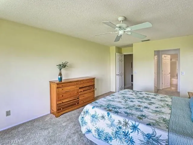 Bedroom with carpet flooring, a textured ceiling, a ceiling fan, and ensuite bathroom