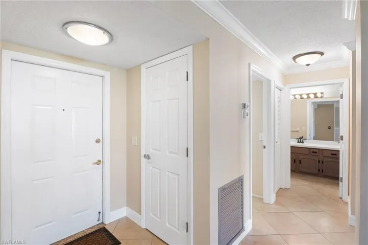 Tiled entrance foyer featuring sink, crown molding, and a textured ceiling