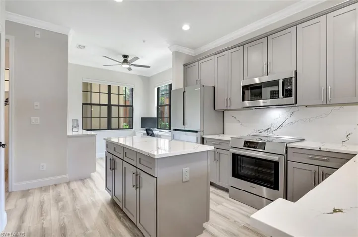 Kitchen with white refrigerator, backsplash, crown molding, a center island, and electric range
