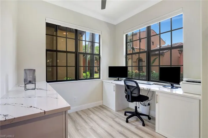 Office space featuring light hardwood / wood-style floors, ornamental molding, a wealth of natural light, and built in desk