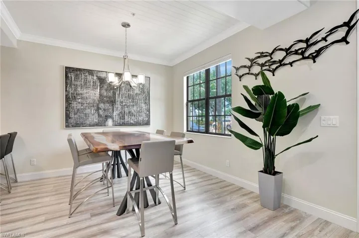 Dining area with an inviting chandelier, light wood-type flooring, and ornamental molding