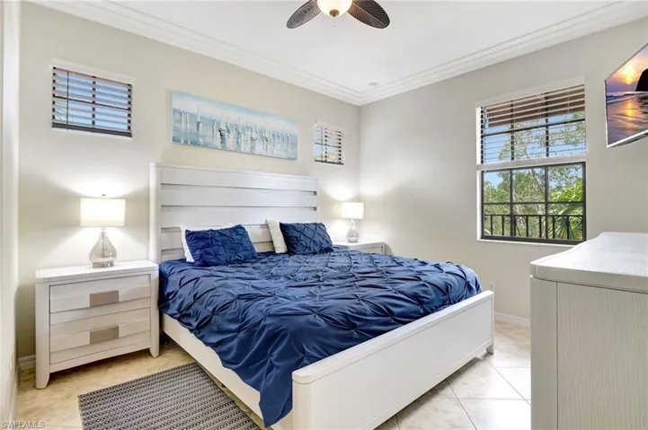 Bedroom featuring light tile patterned floors, ceiling fan, and crown molding