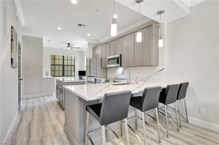 Kitchen with ceiling fan, hanging light fixtures, decorative backsplash, light wood-type flooring, and gray cabinetry