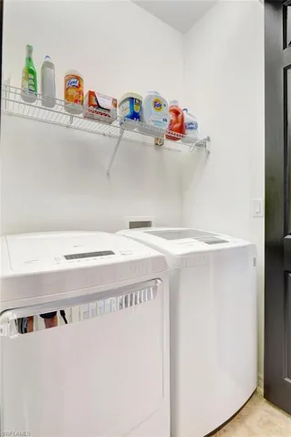 Clothes washing area featuring light tile patterned floors and independent washer and dryer