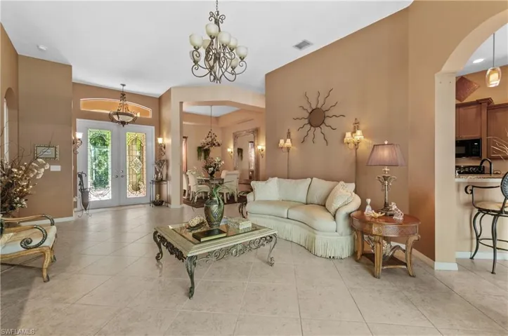Living room with french doors, light tile patterned floors, a chandelier, and sink