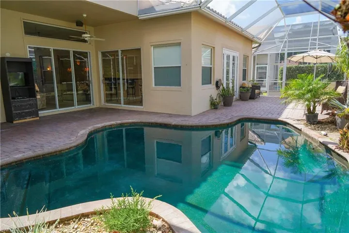 View of pool with ceiling fan, a patio area, and glass enclosure