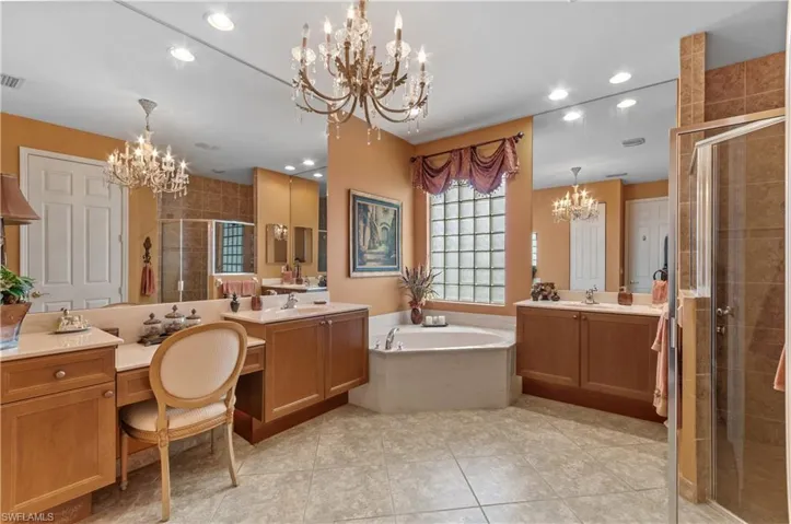 Bathroom with vanity, a chandelier, and separate shower and tub