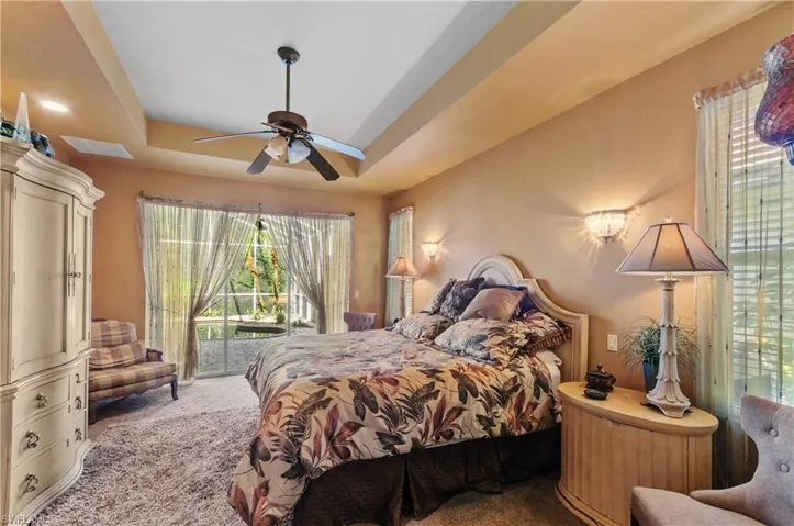 Bedroom featuring light carpet, ceiling fan, a raised ceiling, and access to outside