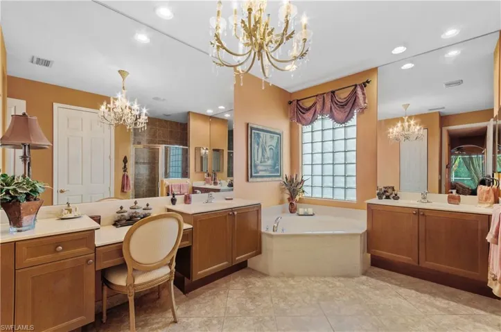 Bathroom featuring vanity, plus walk in shower, a notable chandelier, and tile patterned flooring