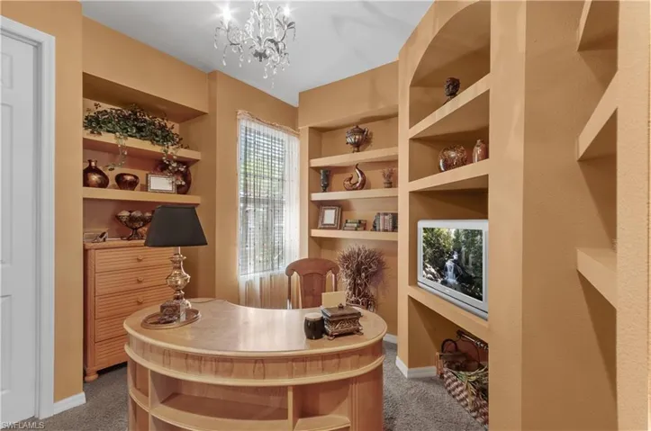 Sitting room featuring built in shelves, carpet flooring, and an inviting chandelier