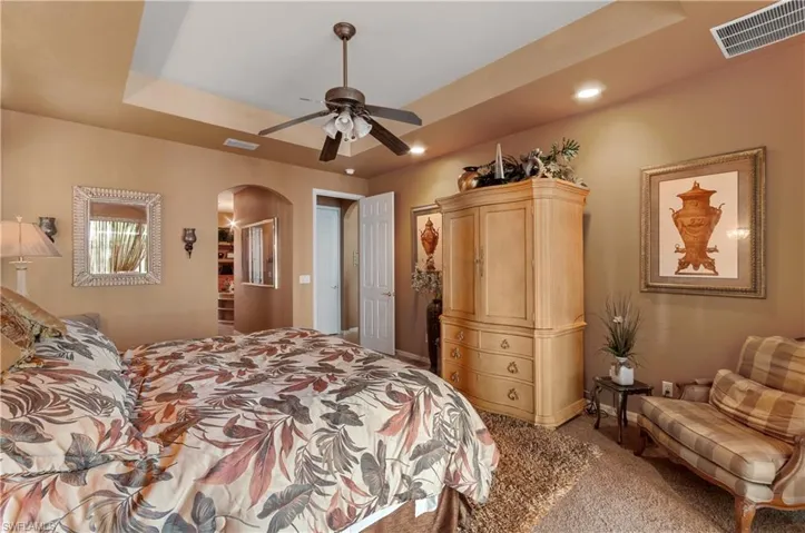 Bedroom featuring carpet flooring, ceiling fan, and a tray ceiling