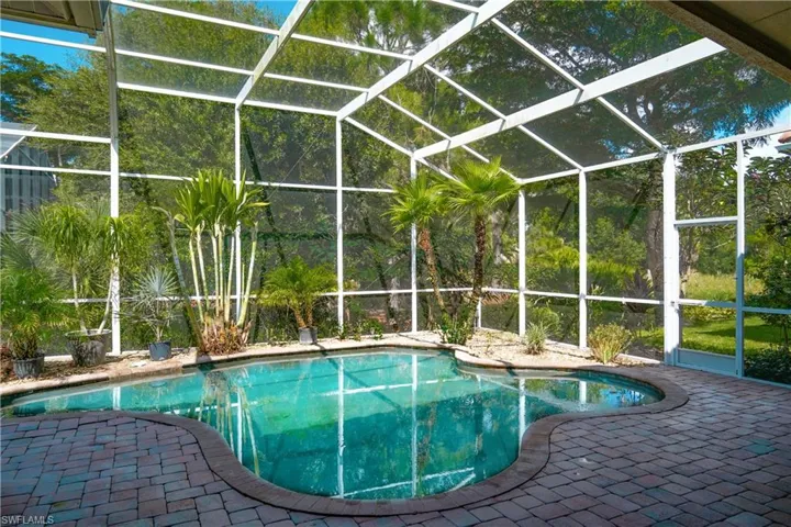 View of pool with glass enclosure and a patio area