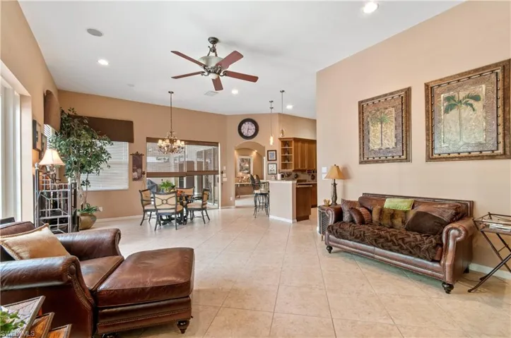 Tiled living room featuring ceiling fan with notable chandelier