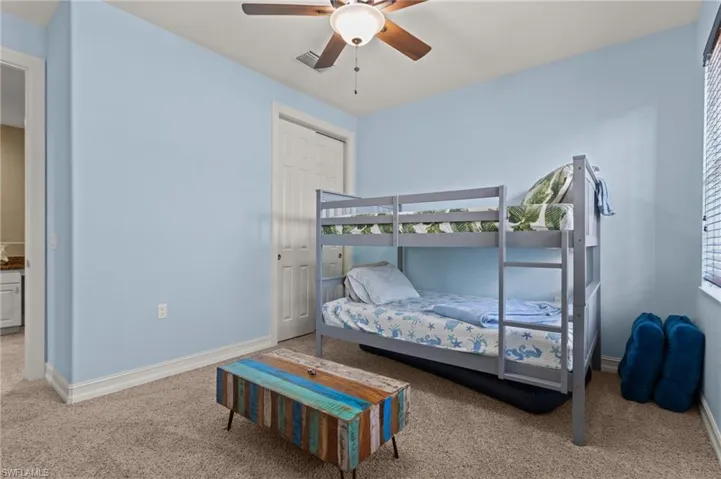Carpeted bedroom featuring baseboards, ceiling fan, and a closet