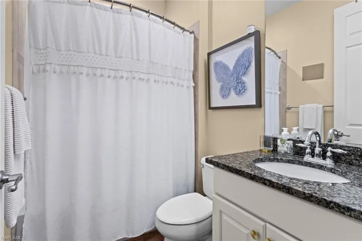 Bathroom featuring toilet, vanity, and a shower with curtain