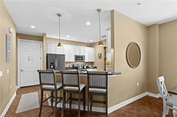 Kitchen featuring stainless steel appliances, dark countertops, baseboards, a kitchen breakfast bar, and a peninsula