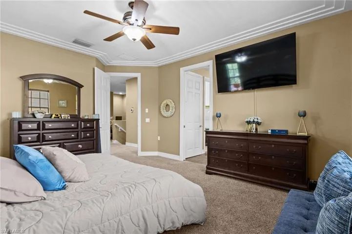 Bedroom with carpet flooring, baseboards, ceiling fan, and crown molding