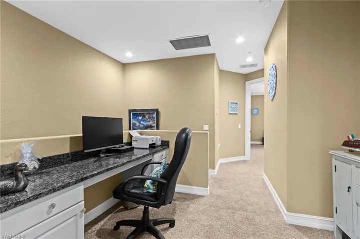 Home office featuring light carpet, baseboards, and built in desk