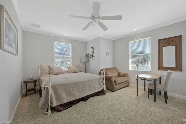 Comfortable guest bedroom, located on second floor with large windows and soft, natural lighting.