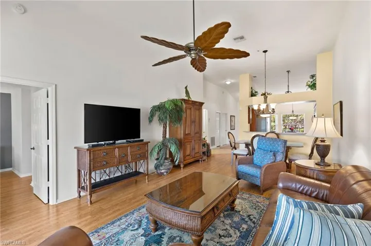 Living room featuring light hardwood / wood-style floors, high vaulted ceiling, and ceiling fan with notable chandelier
