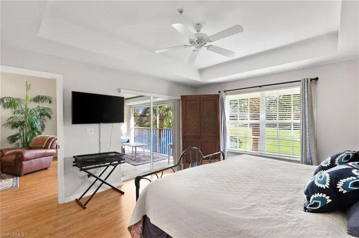 Bedroom featuring access to outside, a tray ceiling, ceiling fan, and light hardwood / wood-style flooring
