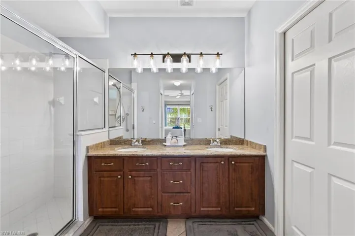 Bathroom with ceiling fan, double sink, walk in shower, tile floors, and large vanity