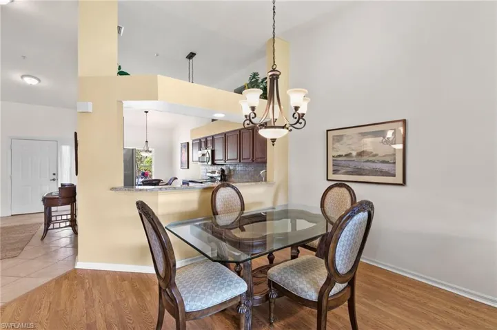 Dining area with a notable chandelier, high vaulted ceiling, and hardwood / wood-style flooring