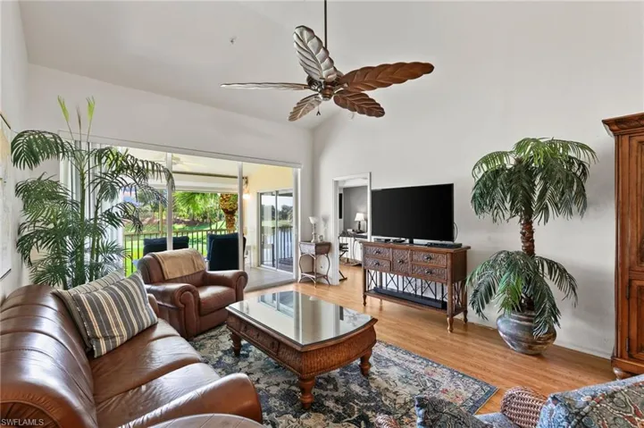 Living room with high vaulted ceiling, hardwood / wood-style flooring, and ceiling fan