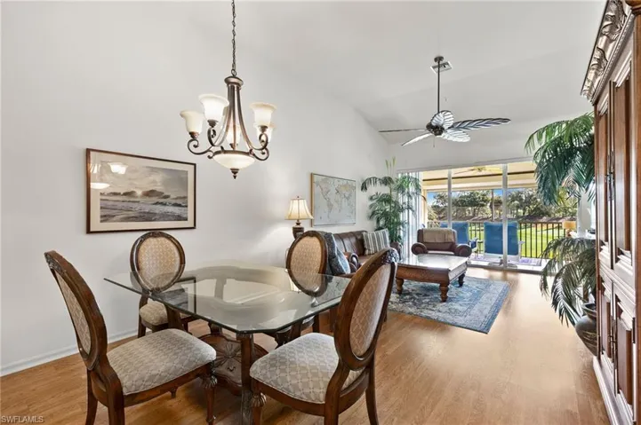 Dining area with ceiling fan with notable chandelier, hardwood / wood-style floors, and lofted ceiling