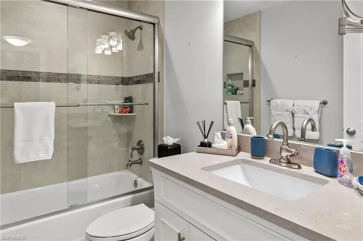 Bathroom featuring vanity and bath / shower combo with glass door