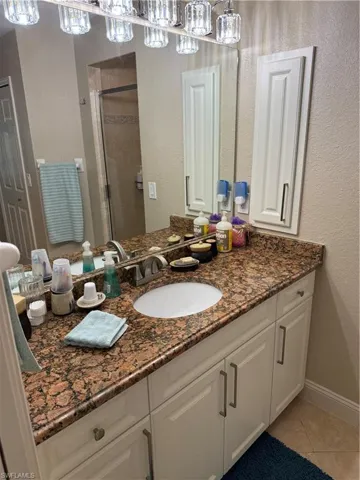 Primary Bathroom #2 featuring a textured wall, vanity, light tile patterned flooring, and a shower stall