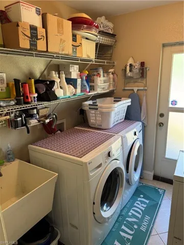 Laundry area featuring separate washer and dryer, light tile patterned flooring, and a textured wall