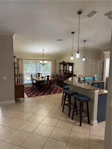 Living room featuring ornamental molding, light tile patterned flooring, suspended lighting, ceiling fan, and a brick fireplace