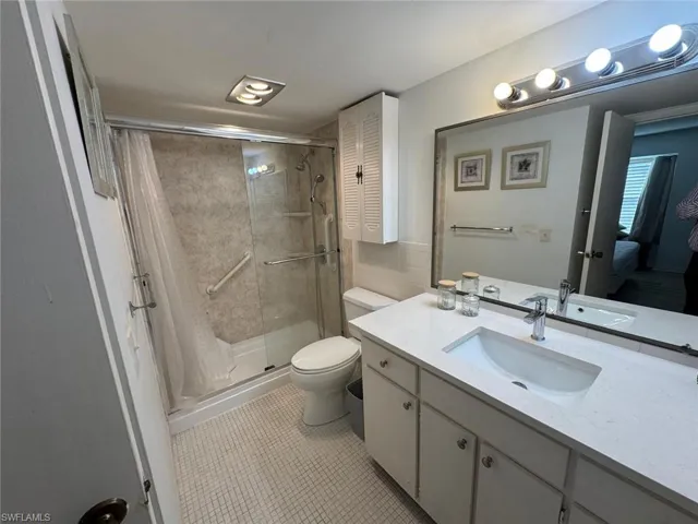 Bathroom with a shower with shower curtain, vanity, tile patterned flooring, and toilet