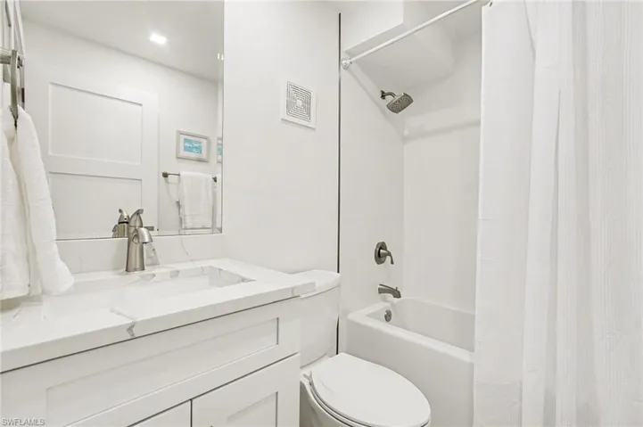 Bathroom featuring a white vanity with an integrated rectangular sink, a stone-finish countertop, and a brushed nickel faucet