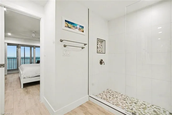 Glass-enclosed shower with white tiled walls and a natural stone pebble floor