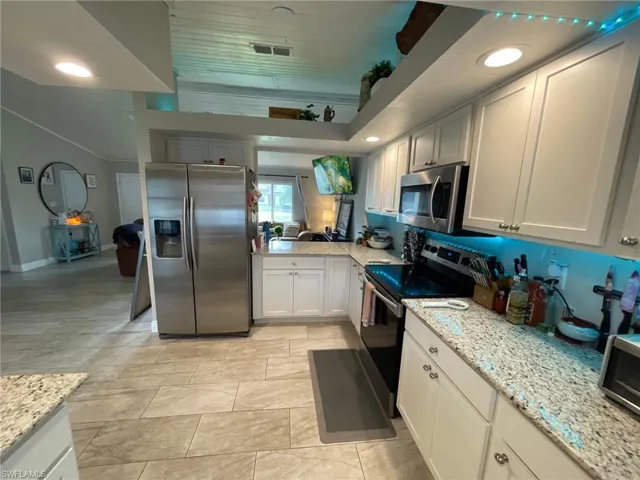 Kitchen with appliances with stainless steel finishes, light stone counters, and baseboards